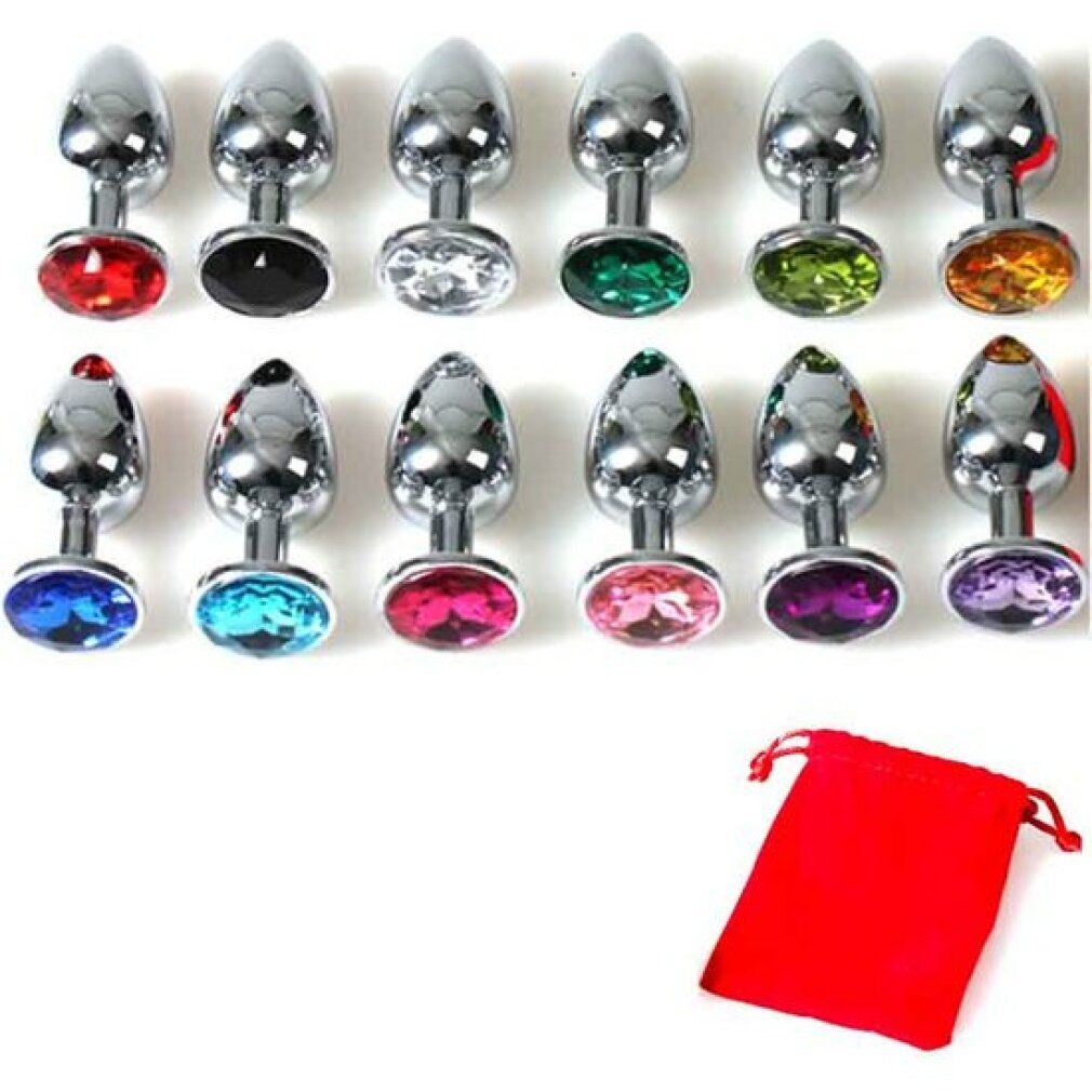 Mehrere Analplugs mit farbigen Schmucksteinen. Metall, glänzend. Konische Form. Roter Beutel daneben.