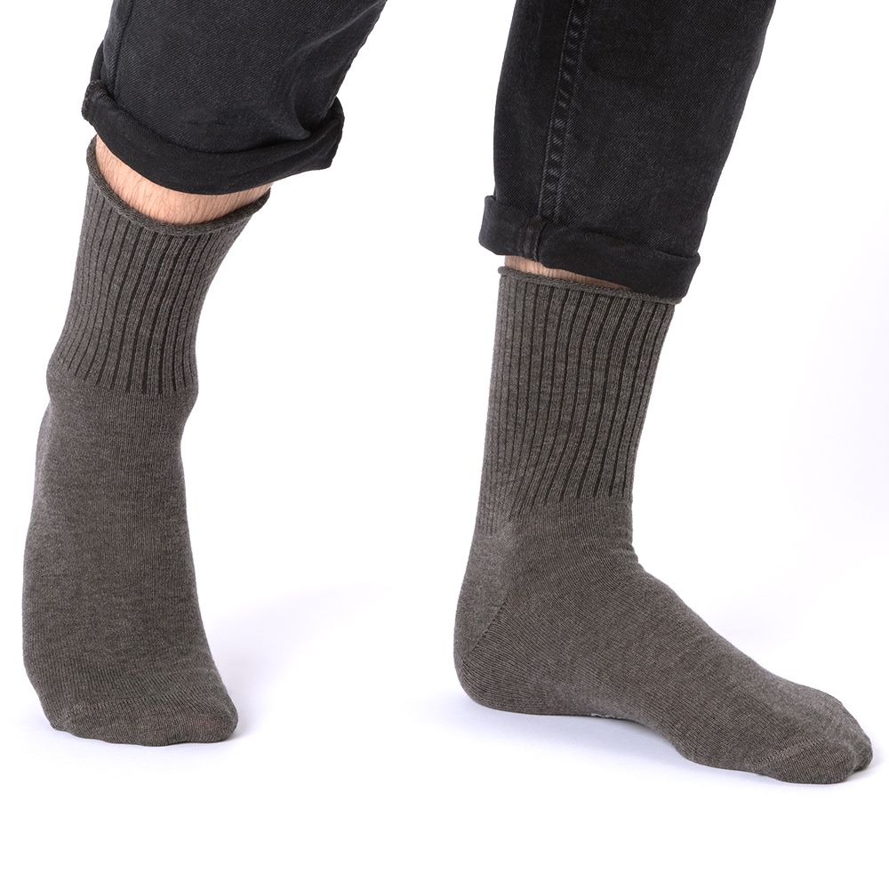 Braune Socken an den Füßen einer Person. Rippstrickbündchen. Schwarze Hose. Aufdruck am Fuß.