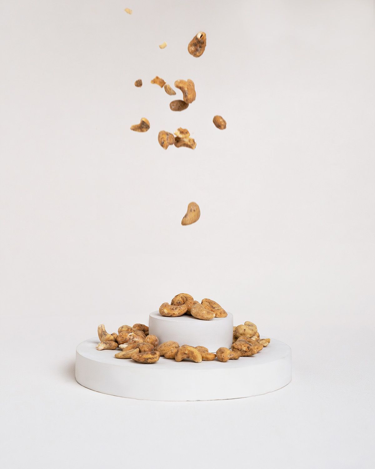 Cashewkerne fallen auf ein Podest. Einige Kerne liegen bereits auf dem Podest.