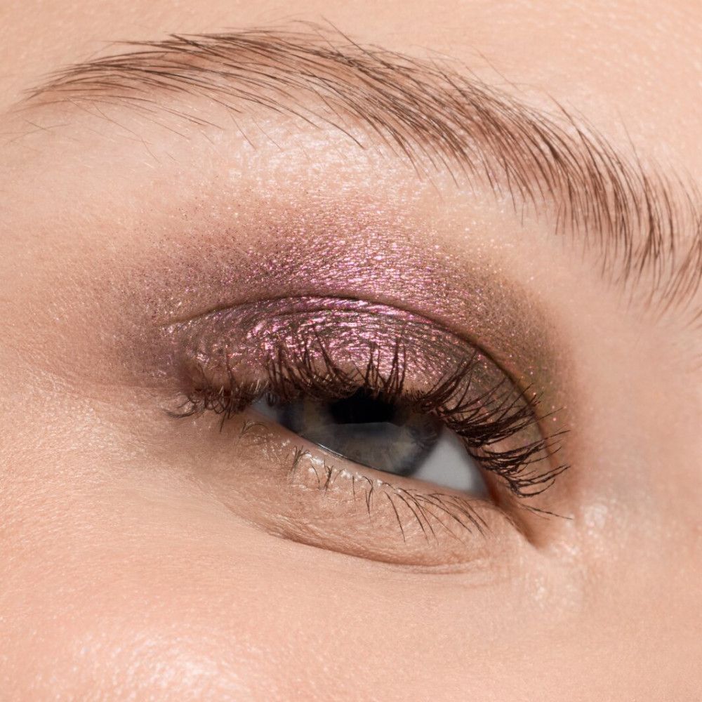 Nahaufnahme eines Auges mit rosa und braunem Lidschatten. Die Wimpern sind getuscht.