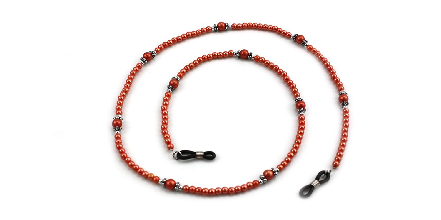 Brillenkette mit roten Perlen und silberfarbenen Elementen. Schwarze Brillenhalterungen an den Enden. Auf weißem Hintergrund.