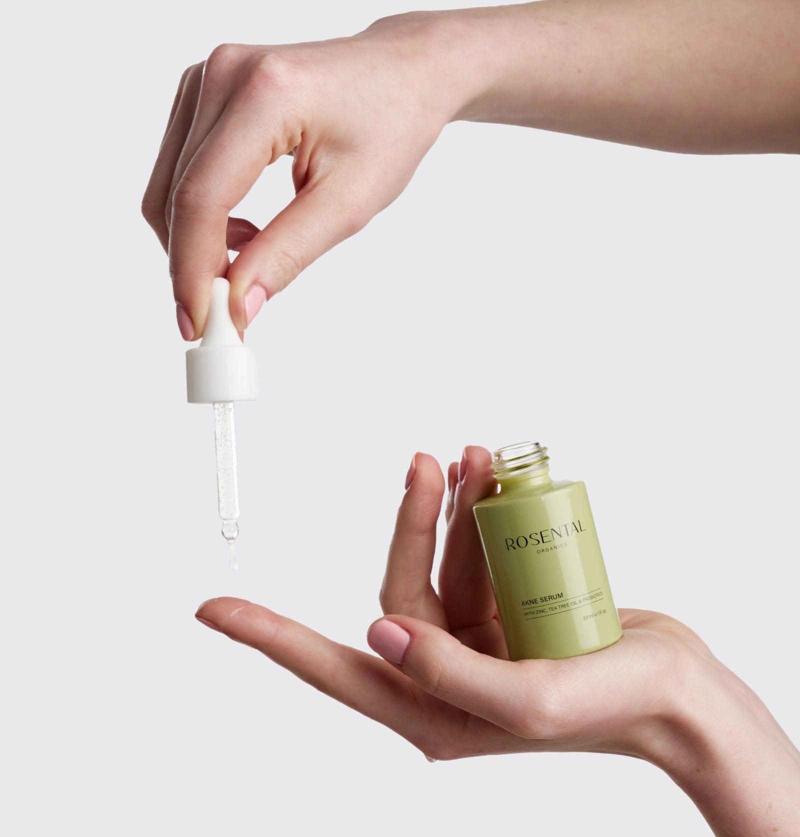 Hände halten eine grüne Flasche und eine Pipette. Tropfen Serum fällt aus der Pipette.