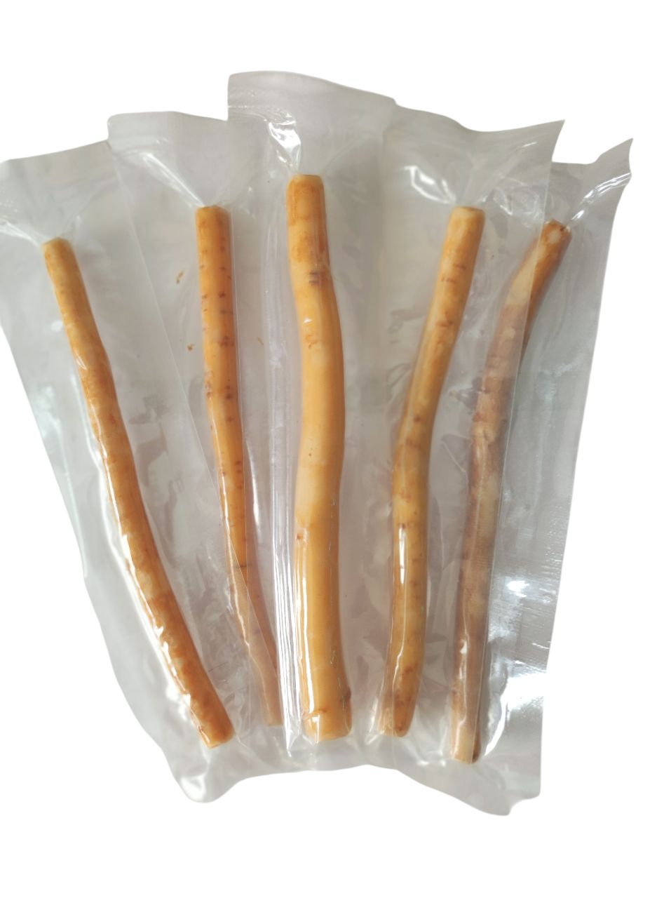 Mehrere Miswak-Sticks in Folie verpackt. Die Sticks sind hellbraun und zylindrisch.