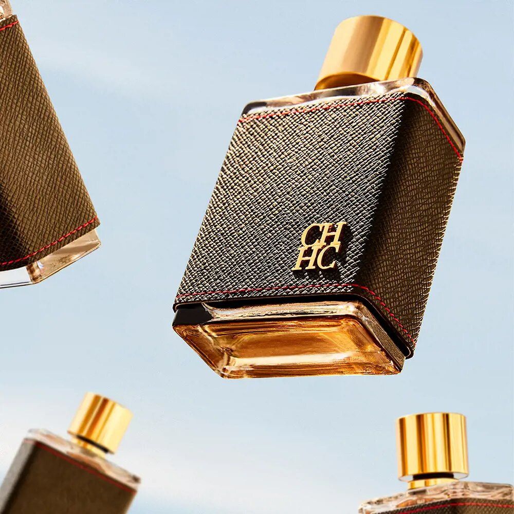 Mehrere Eau de Toilette-Flakons mit schwarzem Lederimitat, roter Naht und goldenem Verschluss. Auf blauem Hintergrund.