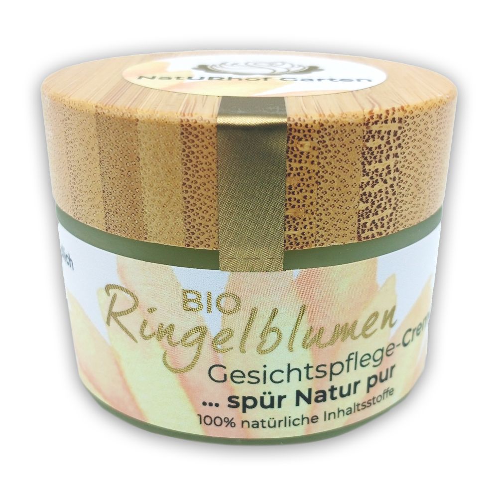Creme-Tiegel mit Holzdeckel. Aufschrift: BIO Ringelblumen Gesichtspflege-Creme. Grün-weißes Etikett. Goldfarbener Verschluss.