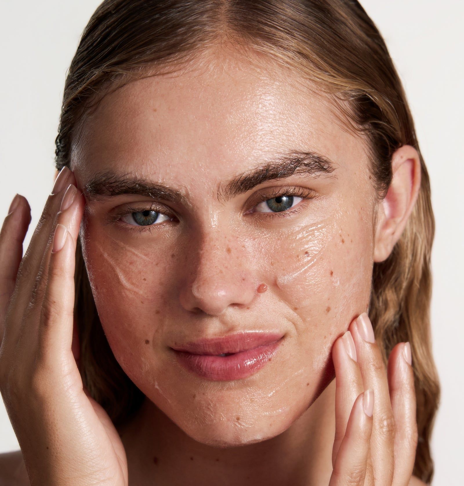 Nahaufnahme einer Frau, die das Cleansing Gel auf ihr Gesicht aufträgt. Gel ist sichtbar auf der Haut.