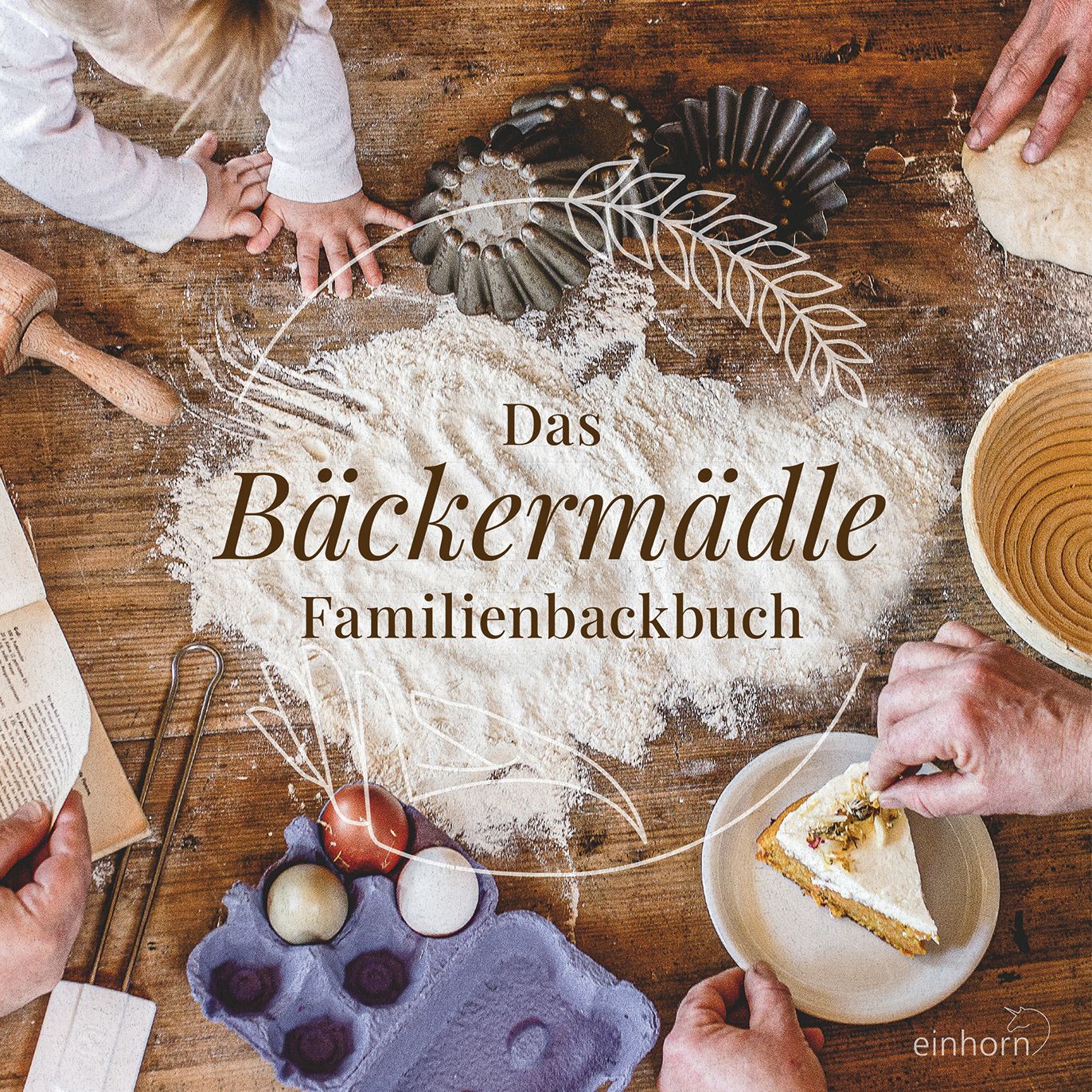 Buchcover "Das Bäckermädle Familienbackbuch" auf Holztisch mit Zutaten und Händen. Titel in brauner Schrift, umgeben von Mehl.