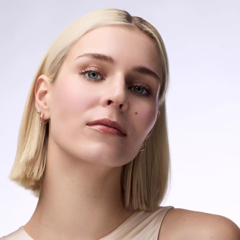 Porträt einer Frau mit blonden Haaren. Sie blickt direkt in die Kamera. Helle Haut, dezentes Make-up.