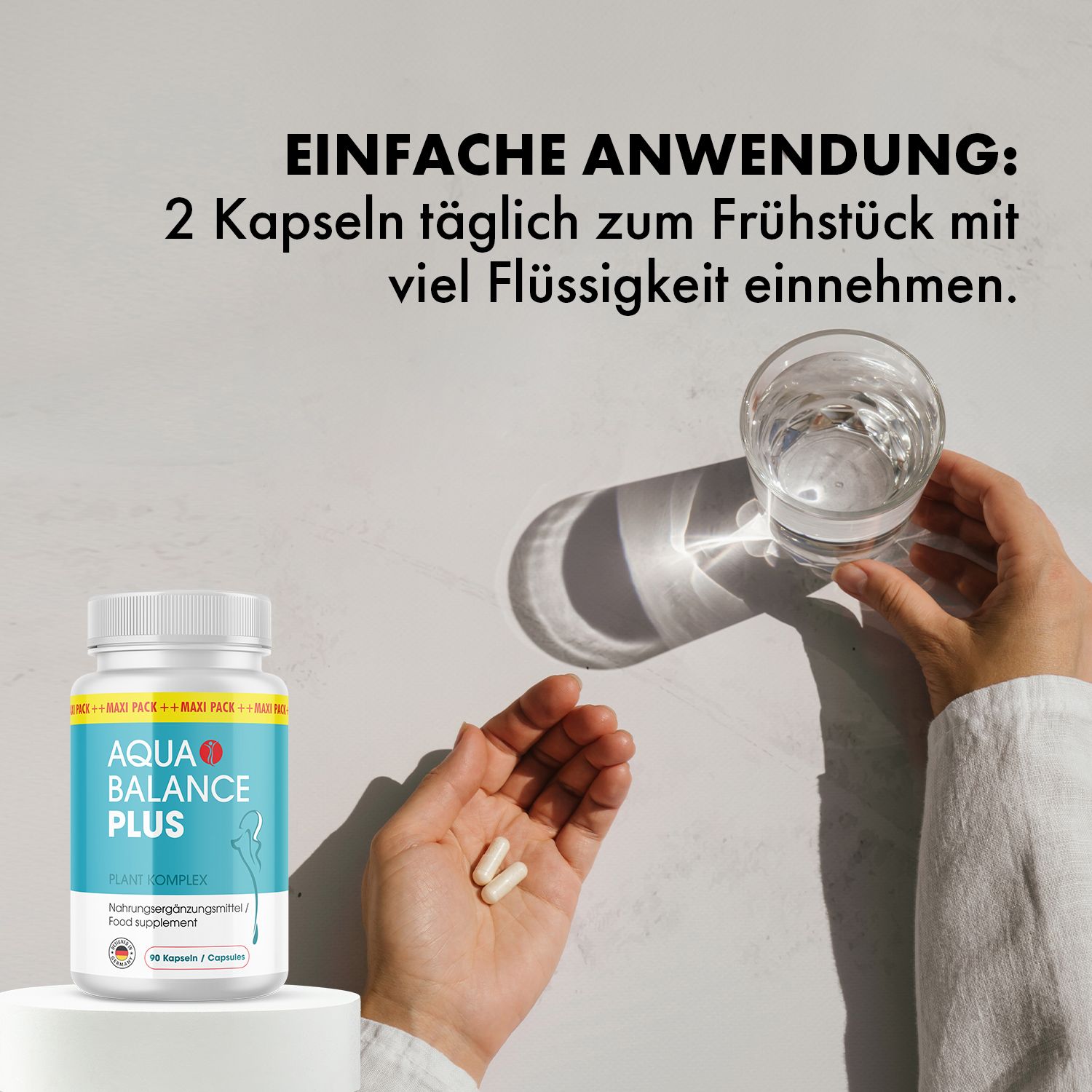 Hände halten zwei Kapseln neben Aqua Balance Plus Flasche und Glas Wasser. Text: 2 Kapseln täglich zum Frühstück.