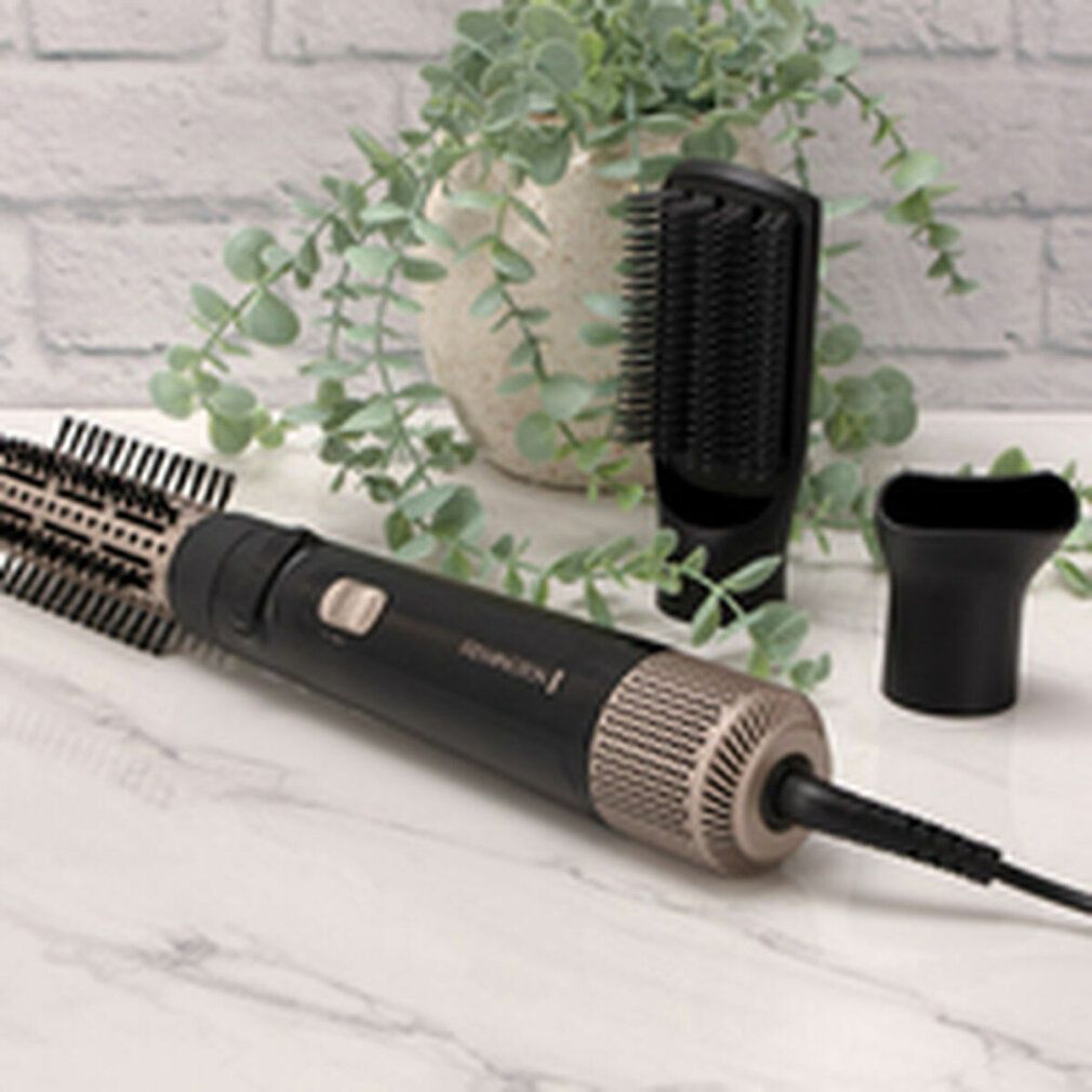 Remington Multi-Warmluftstyler mit Bürstenaufsatz und Zubehör. Schwarz und goldfarben. Auf einem Tisch mit Pflanzen.