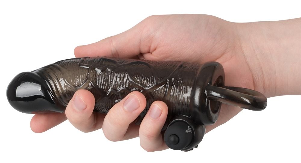 Schwarzes Verlängerungsstück in einer Hand gehalten. Ring, Noppen und Aufsatz sichtbar. Aus Silikon.