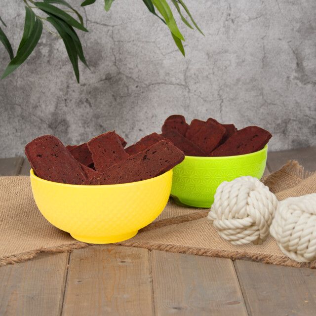 Zwei Schalen mit Rindfleischstreifen, gelb und grün. Auf Jutegewebe. Dekorative Knoten.