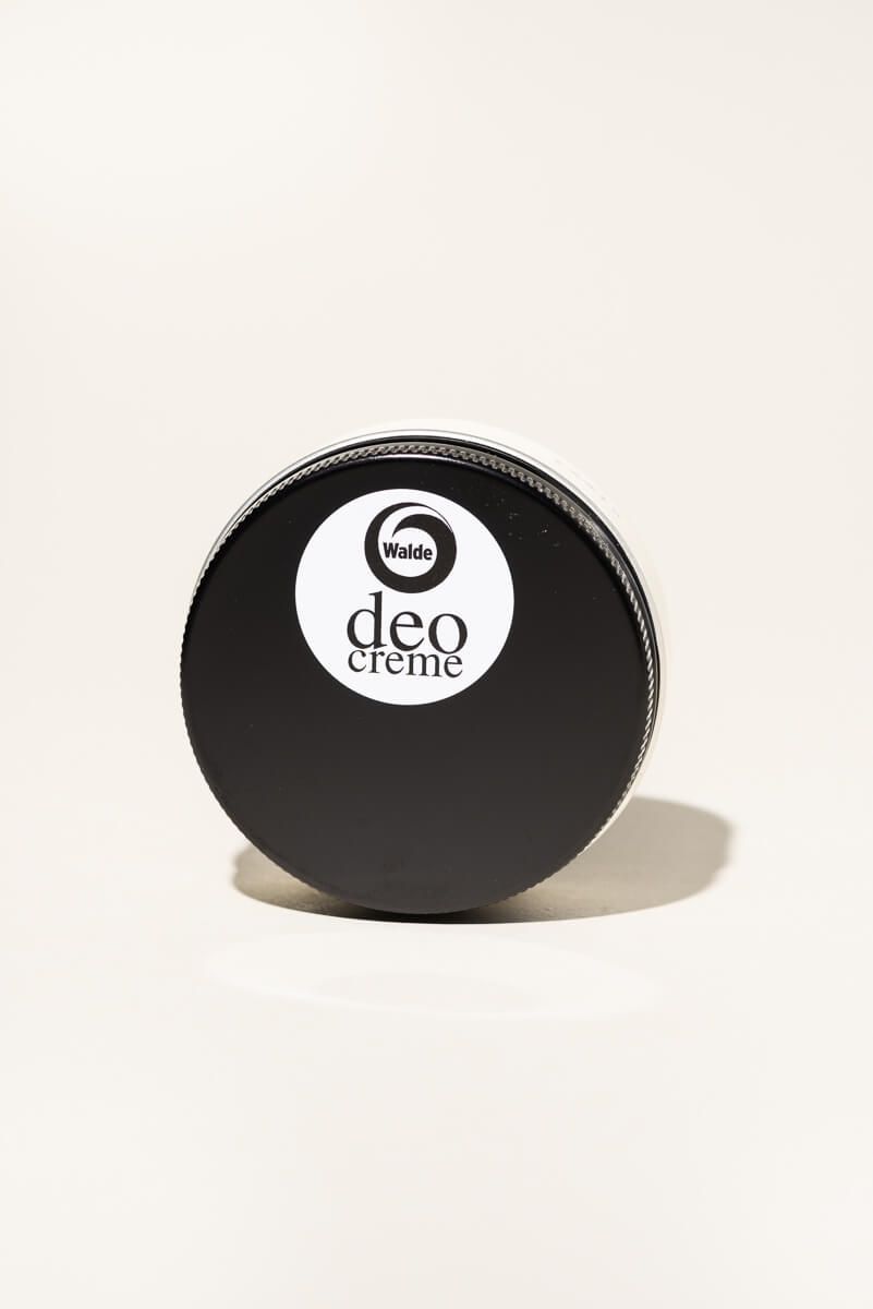 Runde, schwarze Dose mit weißem Etikett. Auf dem Etikett steht "Walde deo creme".