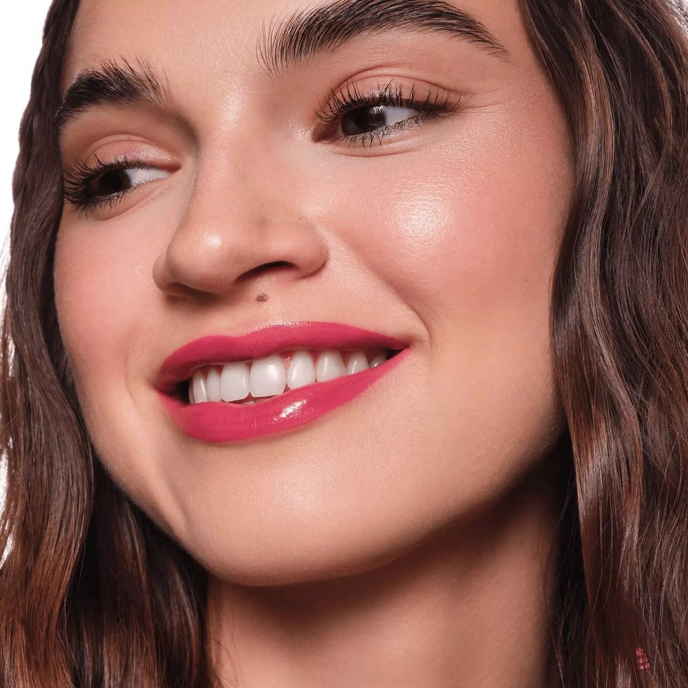 Porträt einer Frau mit rosa Lippen. Sie lächelt und blickt zur Seite.