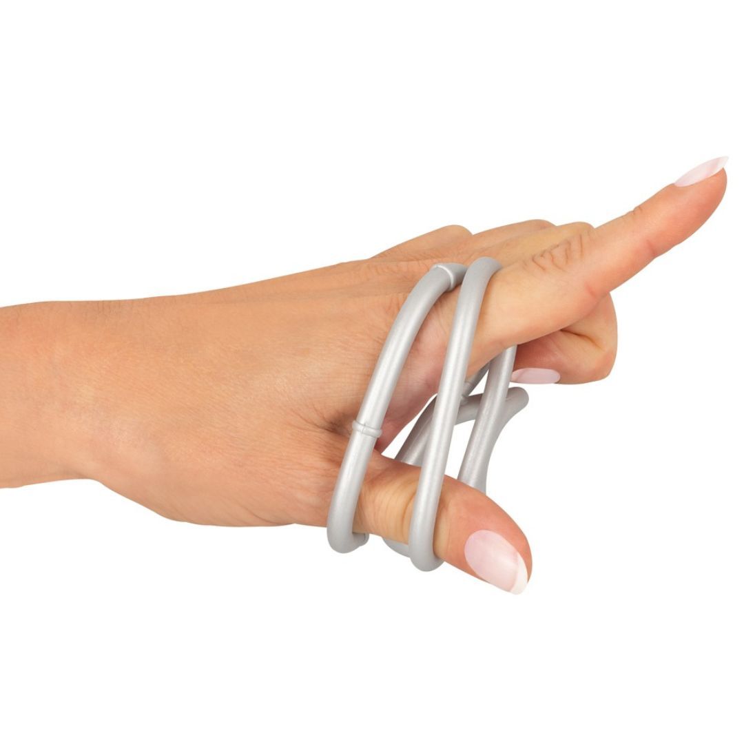 Hand mit silberfarbenem Ring mit drei Öffnungen, der über einem Finger getragen wird. Weißer Hintergrund.