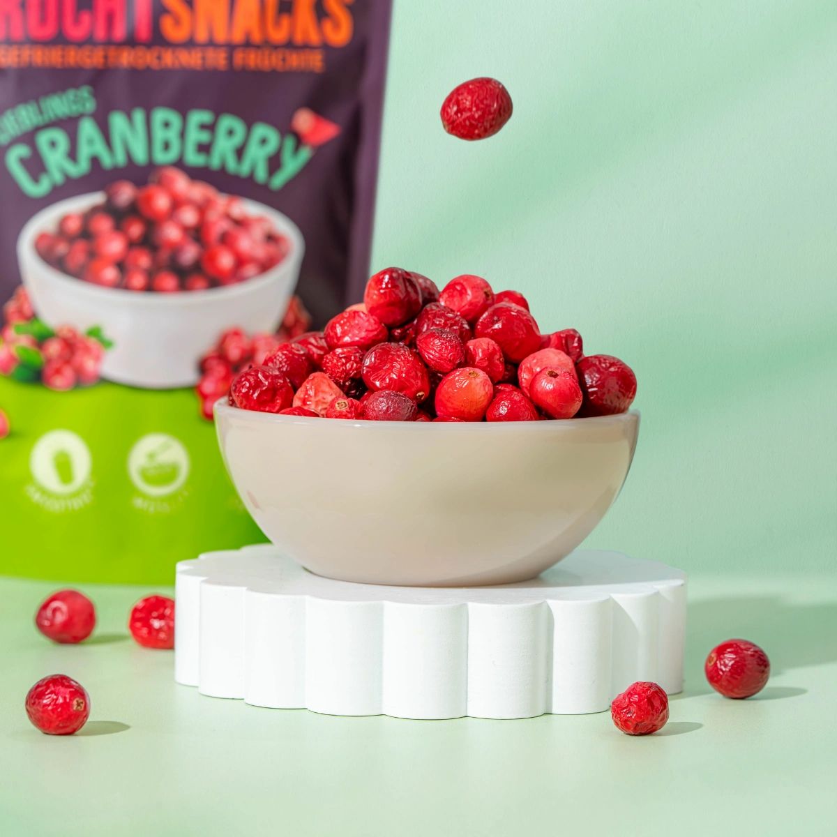 Schale mit Cranberrys auf Podest. Produktverpackung im Hintergrund. Aufschrift: NutriPur, Frucht Snacks, Cranberry.