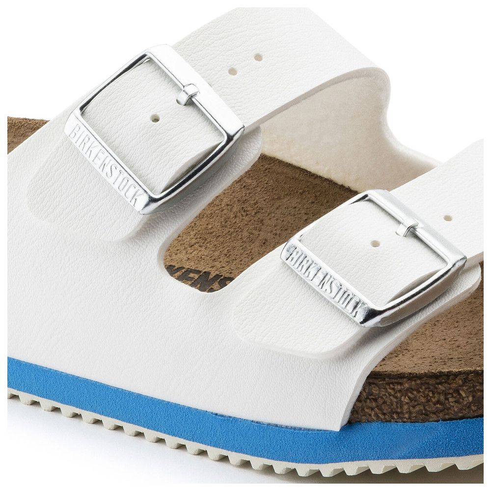 Nahaufnahme einer weißen Birkenstock-Sandale. Zwei Riemen mit silbernen Schnallen. Blaue Sohlenkante. Marke auf Schnallen.