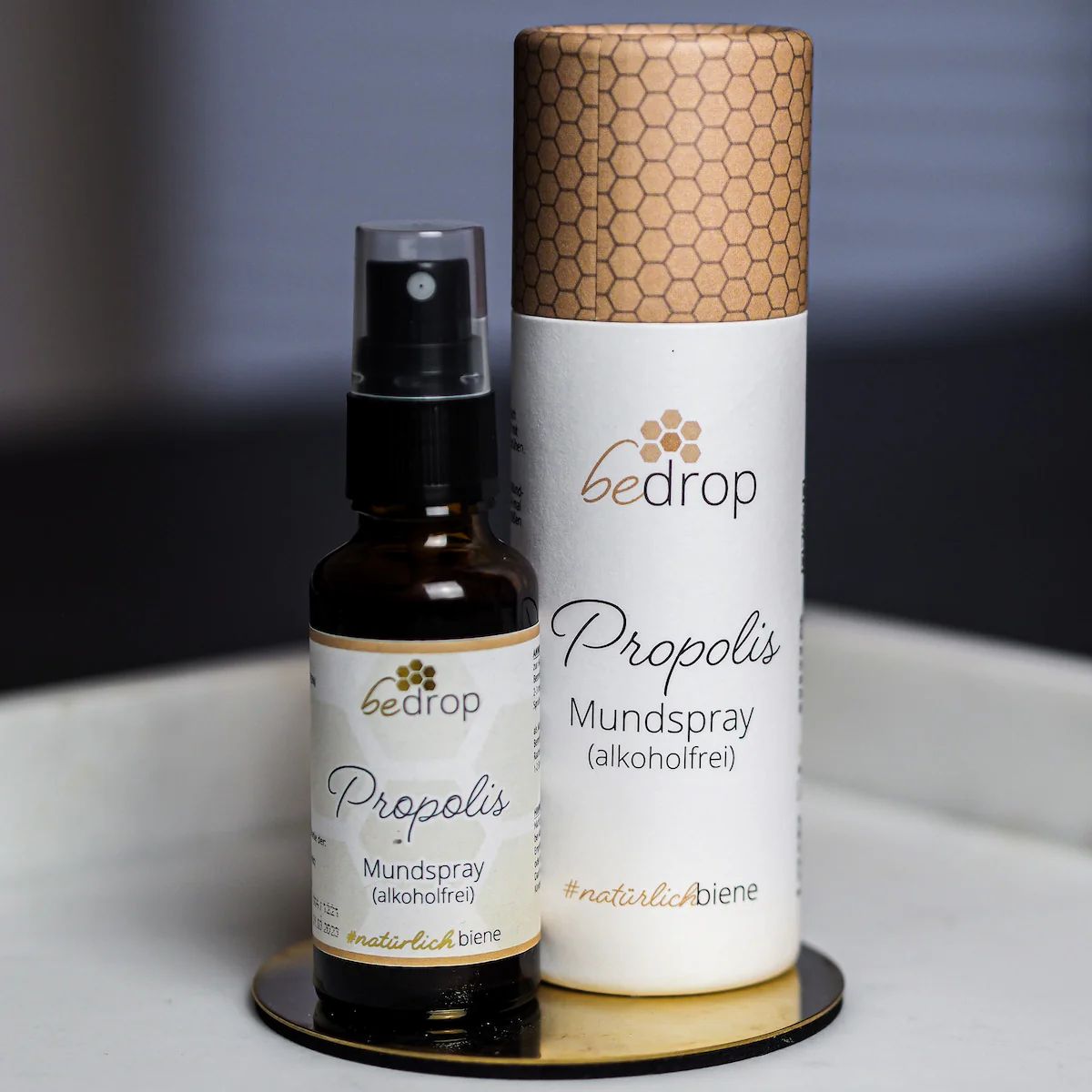 Braune Glasflasche mit schwarzem Sprühkopf und zylindrischer Verpackung. Aufschrift: bedrop Propolis Mundspray.