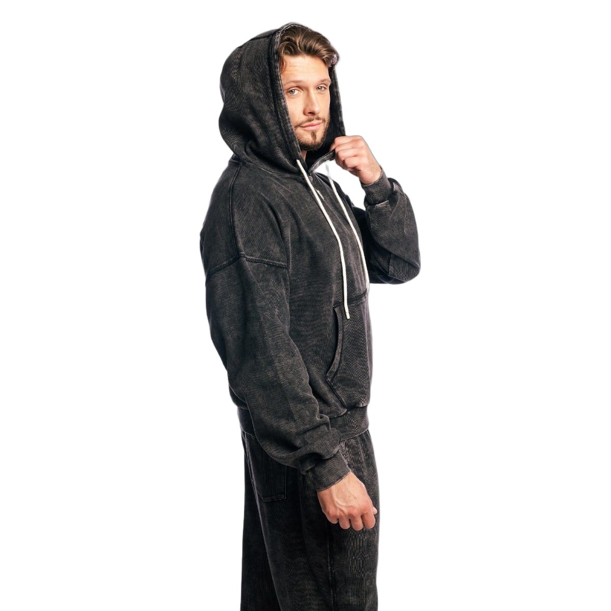 Seitenansicht eines Mannes im Oversized Hoodie in verwaschenem Schwarz mit Kapuze und Kordelzug.
