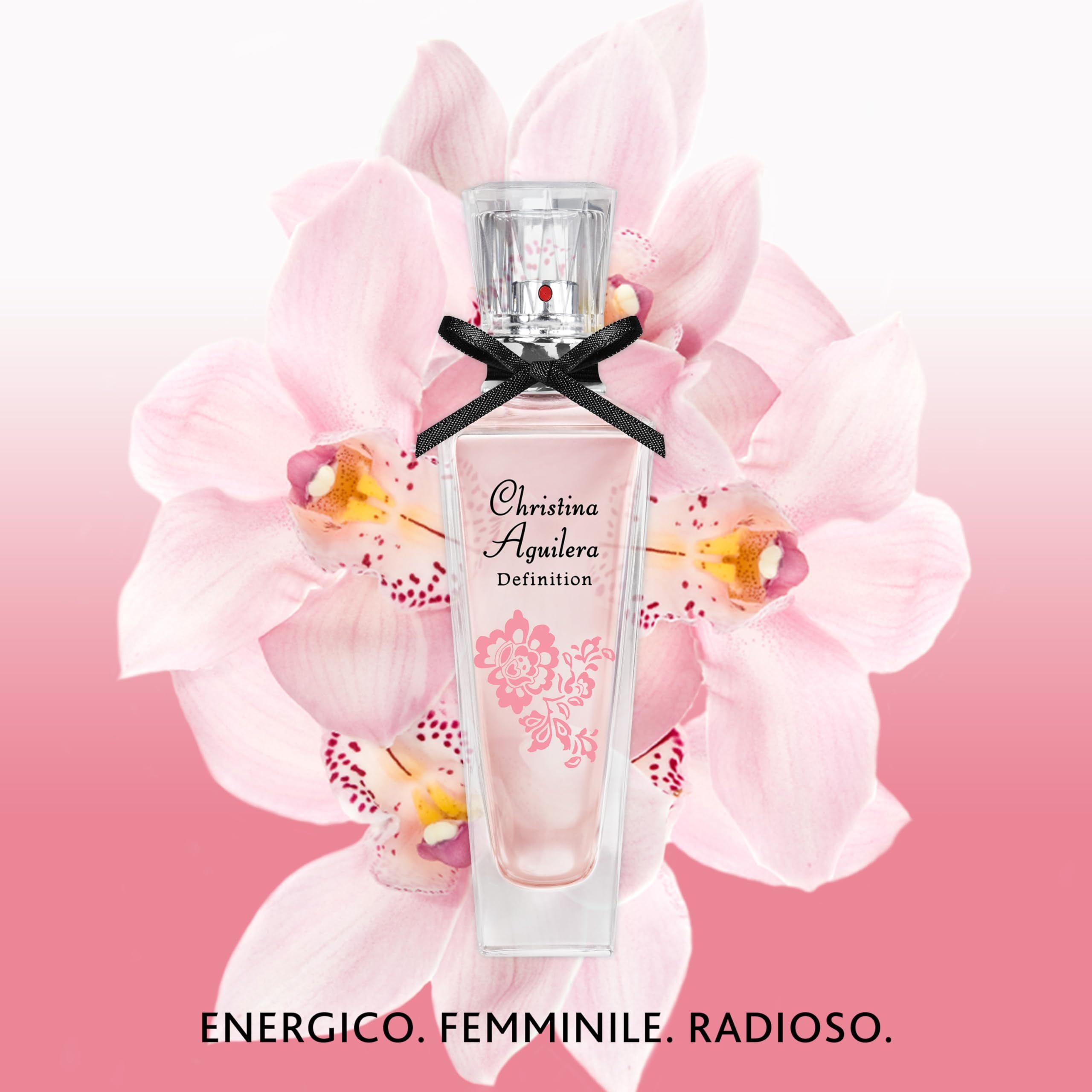 Parfümflakon mit rosa Flüssigkeit, schwarzer Schleife und floralem Design. Aufschrift: Christina Aguilera Definition. Hintergrund: Blüten.