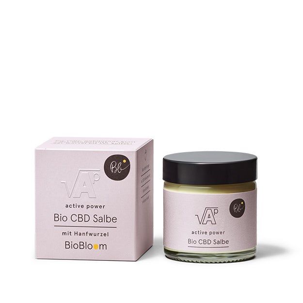 Rosa Verpackung und Glas mit schwarzem Deckel. Aufschrift: Bio CBD Salbe, active power, mit Hanfwurzel. Marke: BioBloom.