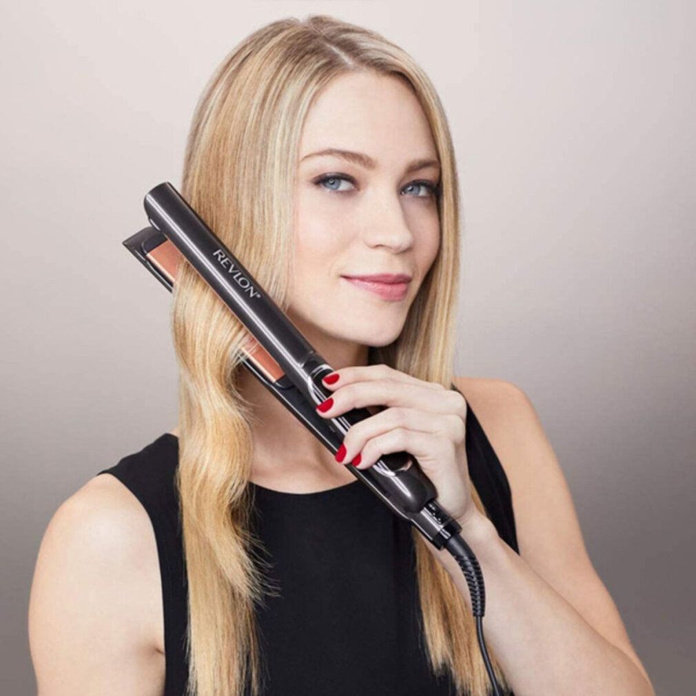 Frau hält Revlon Glätteisen an ihren Haaren. Schwarzes Gehäuse, kupferfarbene Platten. Aufschrift: Revlon.
