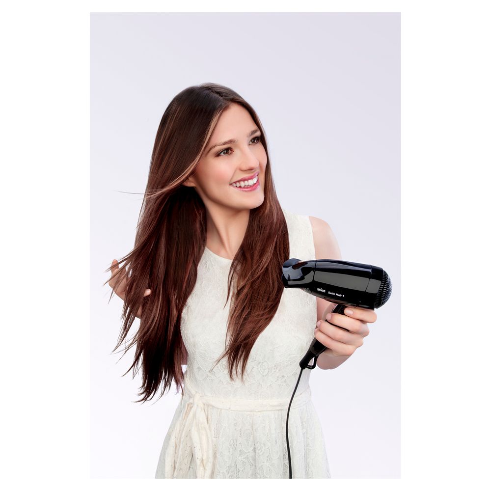 Frau mit langen Haaren hält einen schwarzen Braun Satin Hair 1 Haartrockner.
