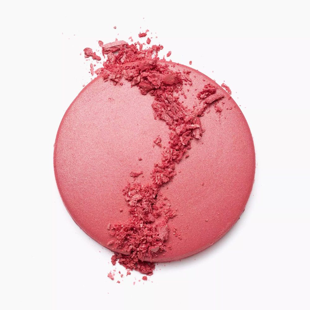 Runder, rosafarbener Rouge-Puder mit zerbröselten Teilen. Auf weißem Hintergrund.