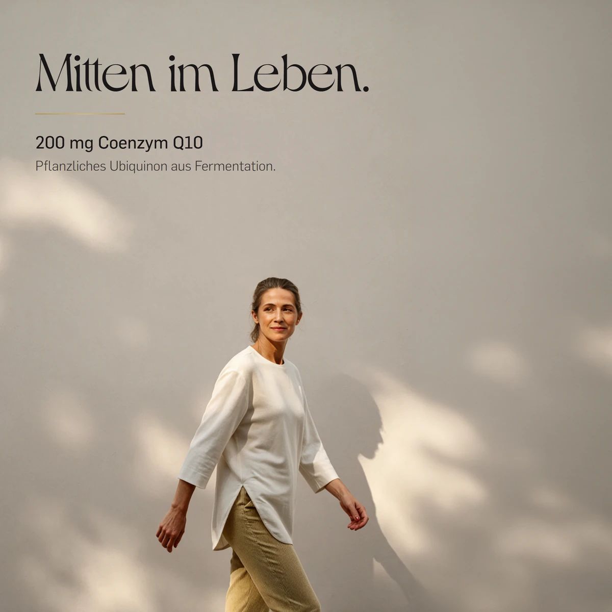 Frau geht an einer Wand entlang, im Hintergrund angedeutet: Coenzym Q10, 200 mg.