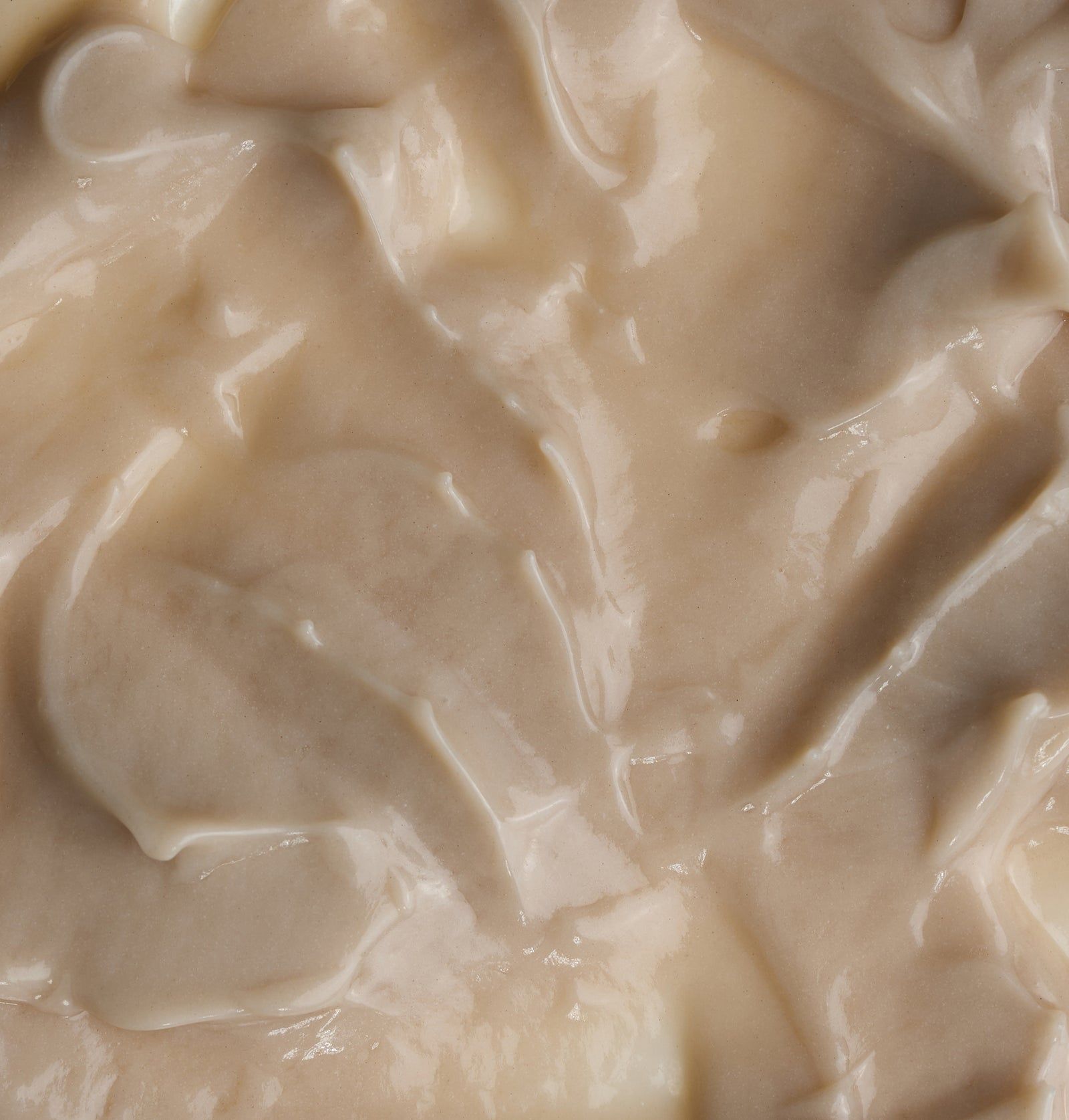 Nahaufnahme von Creme. Cremefarbene, glatte Textur. Creme-Oberfläche mit wellenförmigen Strukturen.