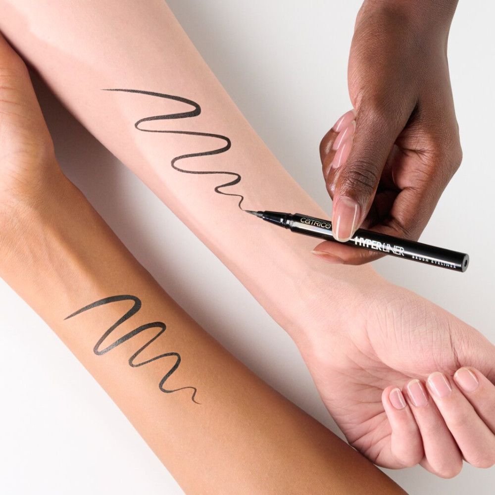 Hände mit schwarzen Eyeliner-Strichen. Der Eyeliner-Stift ist sichtbar. Aufschrift: Catrice, Hyper Liner, Brush Eyeliner.