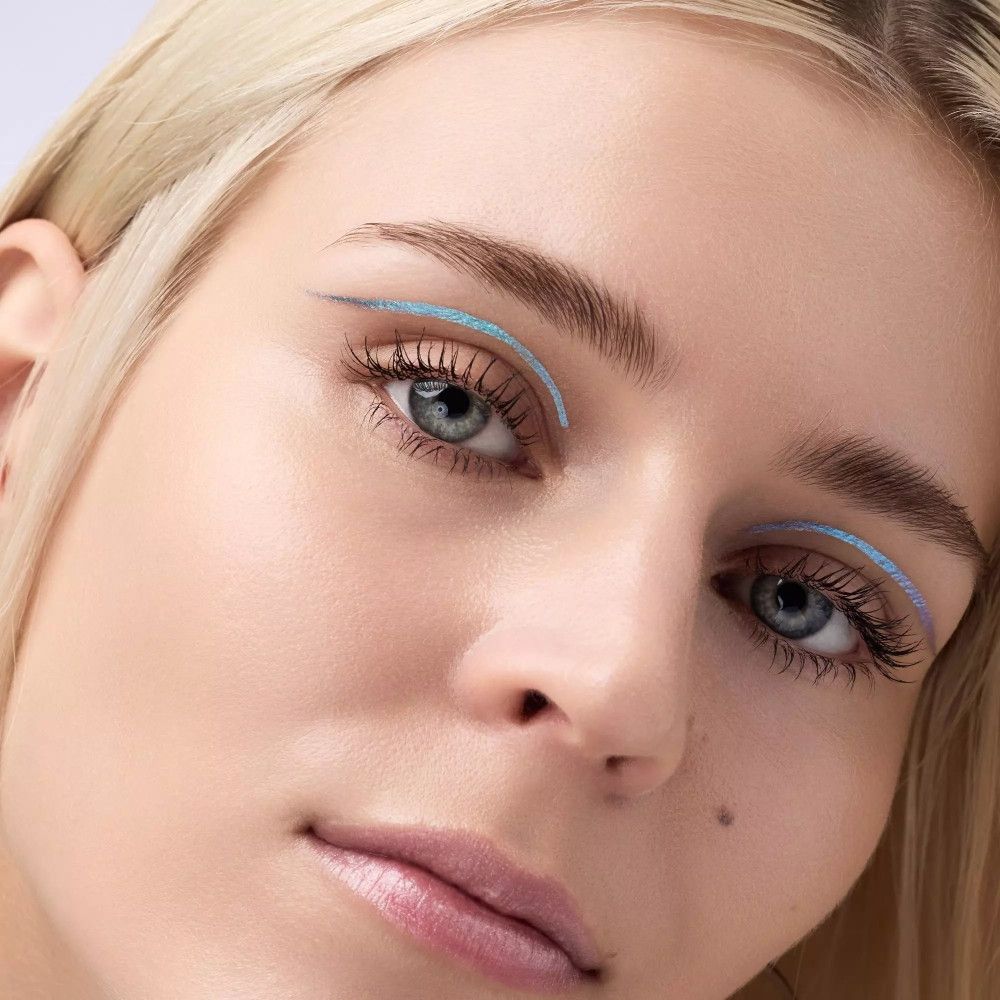 Nahaufnahme eines Gesichts mit blauem Eyeliner. Blonde Frau mit blauen Augen. Eyeliner-Strich am oberen Lid.
