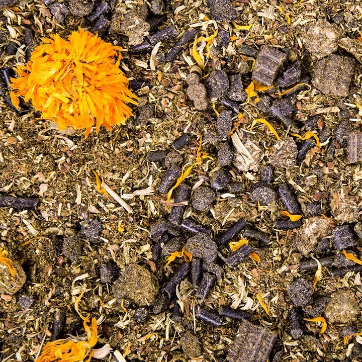 Nahaufnahme von Futtermischung. Sichtbar: getrocknete Blüten, Pellets, Kräuter und andere Bestandteile.
