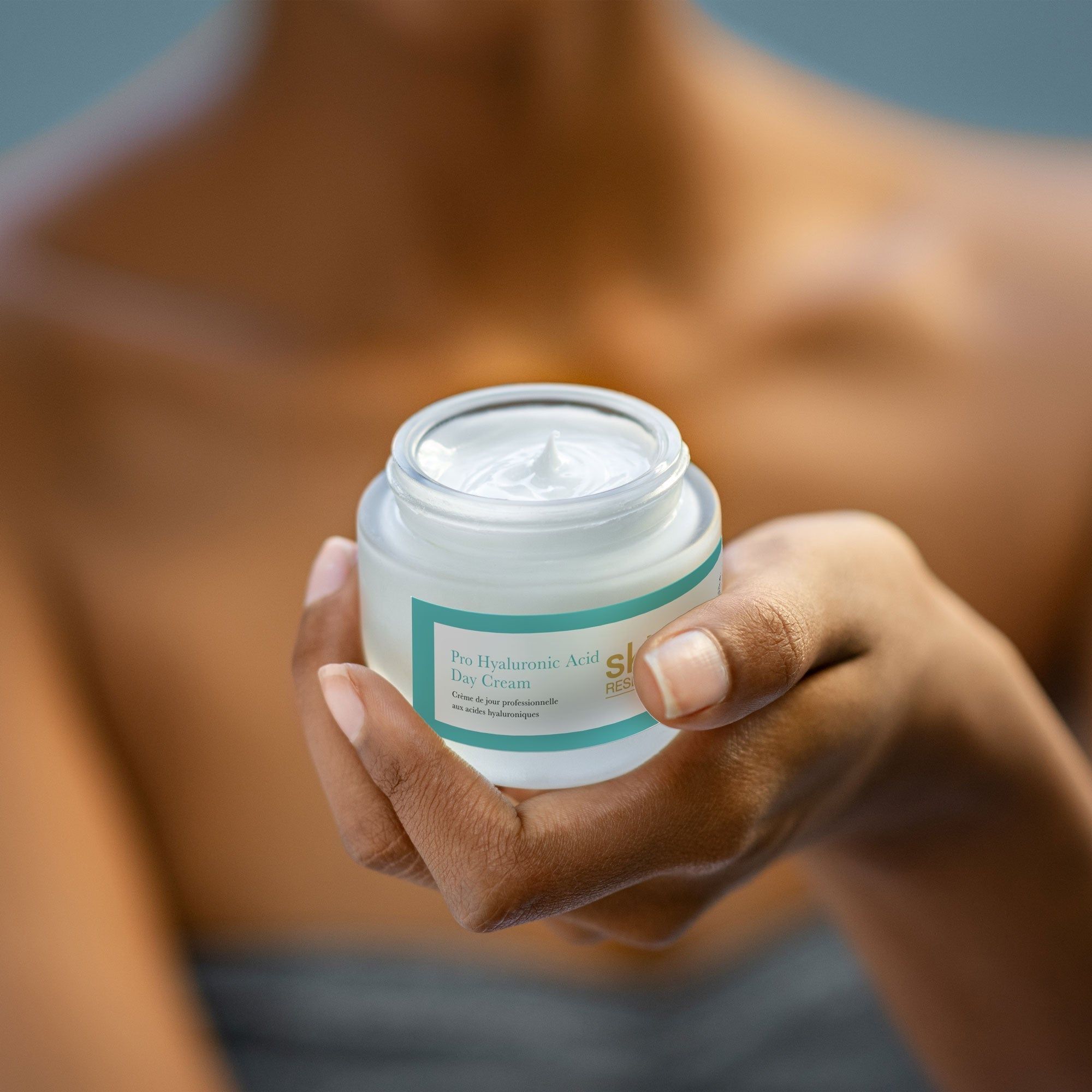 Person hält ein Creme-Glas. Aufschrift: Pro Hyaluronsäure Tagescreme. Marke: skin RESEARCH. Helle Haut.