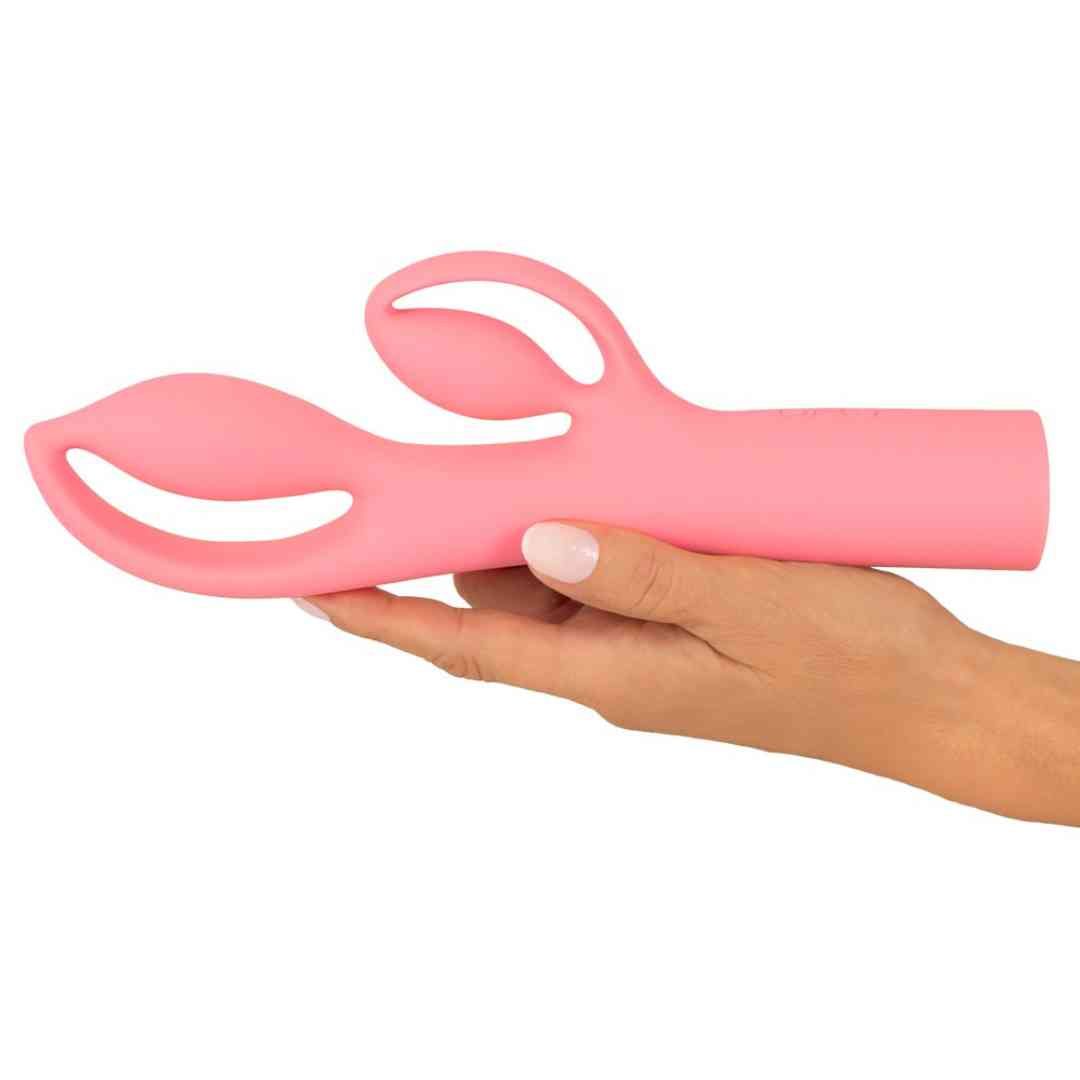 Rosa Vibrator, gehalten in einer Hand. Das Design hat zwei abgerundete Enden und einen länglichen Schaft.