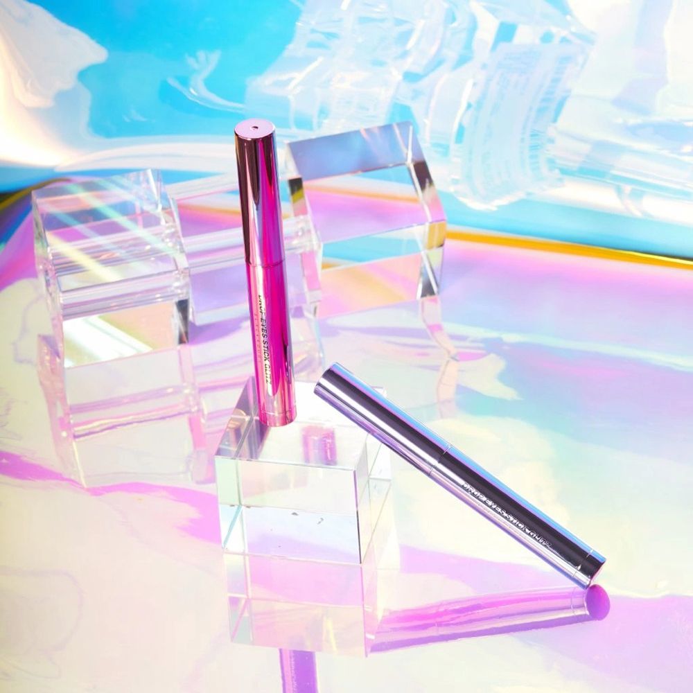 Drop Eyes Stick Glitz Lidschatten in Pink. Auf Glasblöcken. Reflektierender Hintergrund. Produkt und Deckel.
