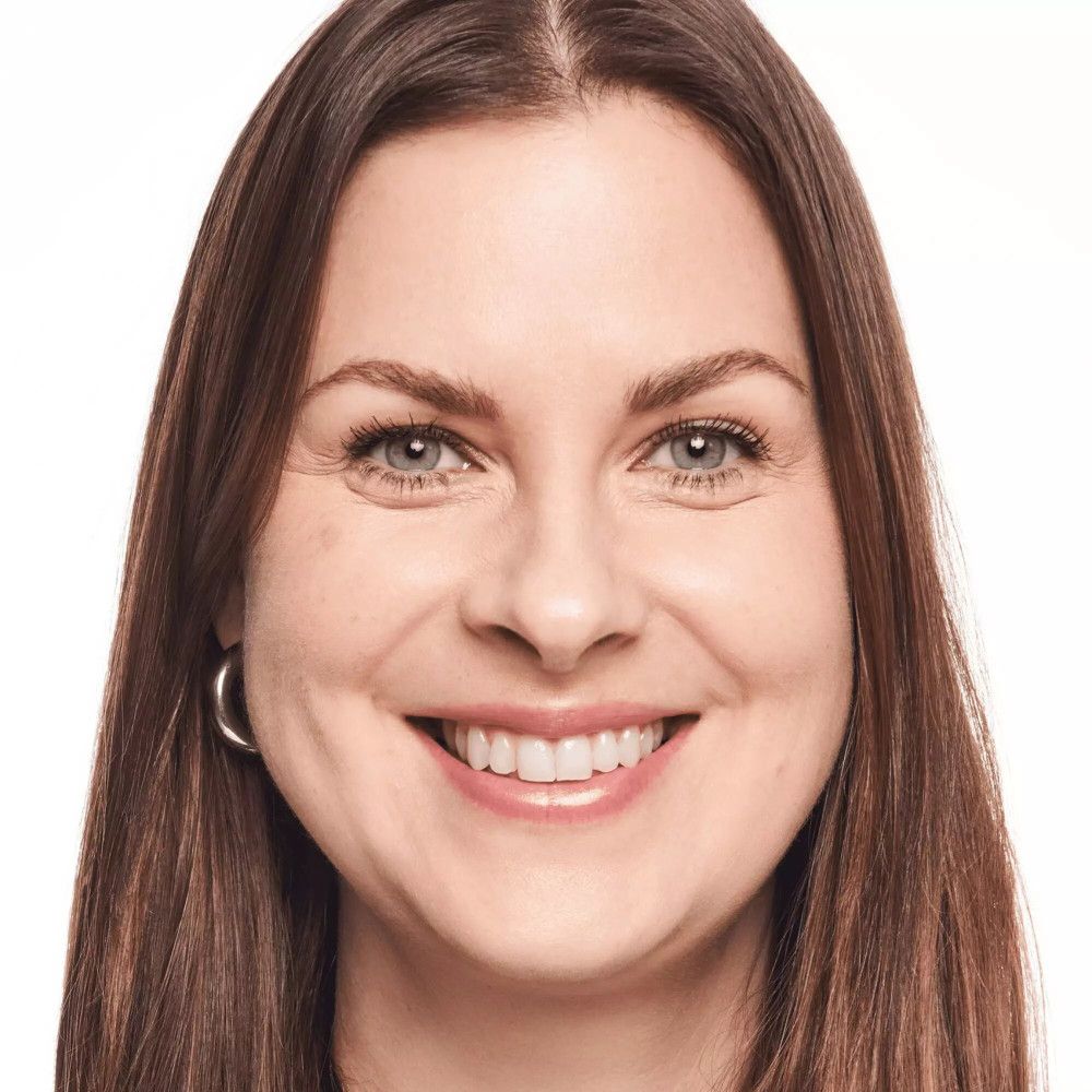 Porträt einer Frau mit hellem Teint. Sie lächelt in die Kamera.