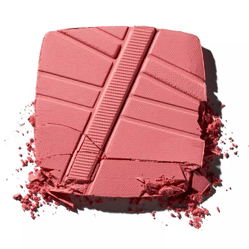 Zerbrochenes Puder-Rouge in Rosa. Geprägtes Muster sichtbar. Einige Bruchstücke liegen verstreut.