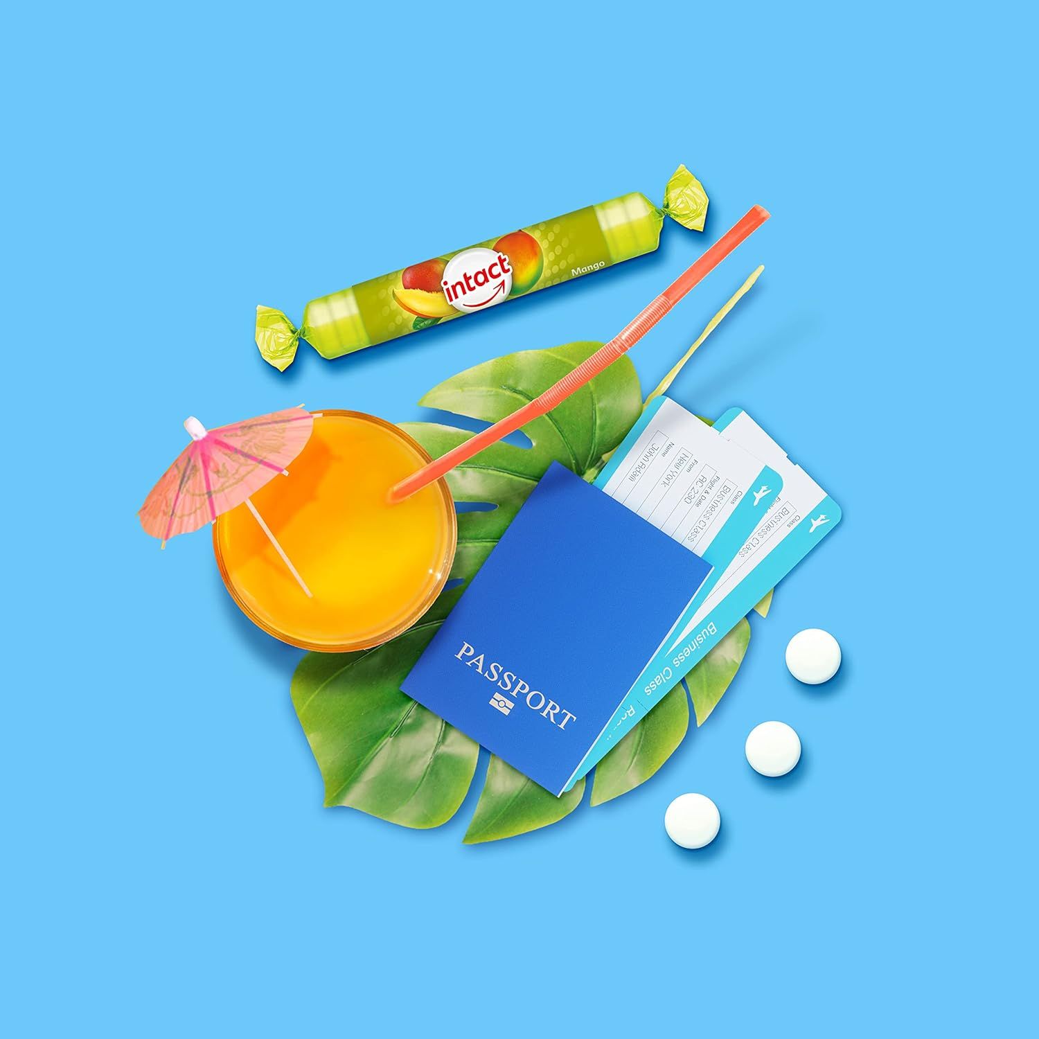 Glas Orangensaft mit Strohhalm, Tabletten, einzeln verpackte Süßigkeit, Pass, Tickets, Blätter. Intact-Logo auf Süßigkeit.