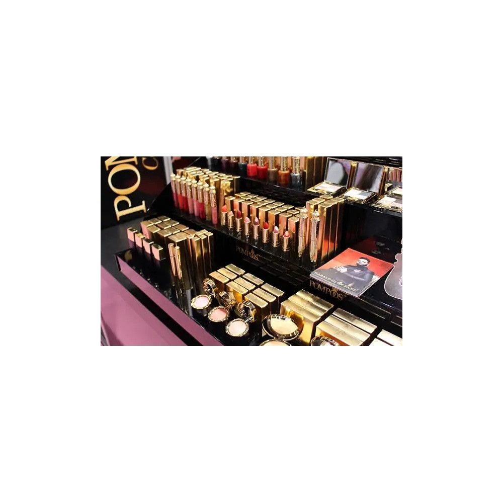 Ausstellung mit Kosmetikprodukten in Gold- und Schwarztönen. Produkte mit "POMPÖÖS"-Logo.
