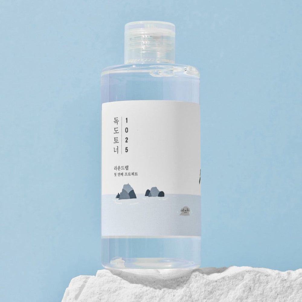 Transparente Flasche mit weißem Etikett. Flasche mit weißem Deckel. Blauer Hintergrund.