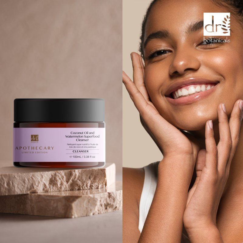 Dr. Botanicals Cleanser neben lächelnder Frau, auf Steinblöcken arrangiert.