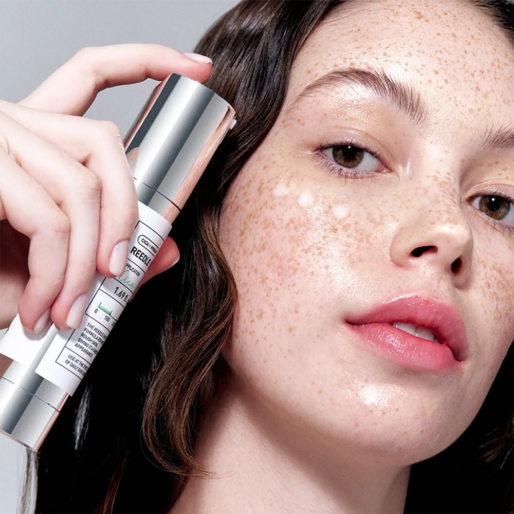 Eine Frau hält eine VT Cosmetics Reedle Shot Ampulle vor ihr Gesicht mit aufgetragener Essenz.