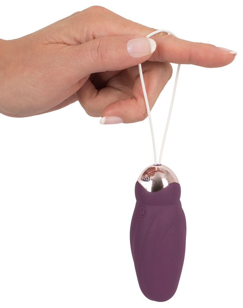 Finger hält Vibrator mit weißer Schlaufe. Lila Vibrator mit goldfarbenen Akzenten.
