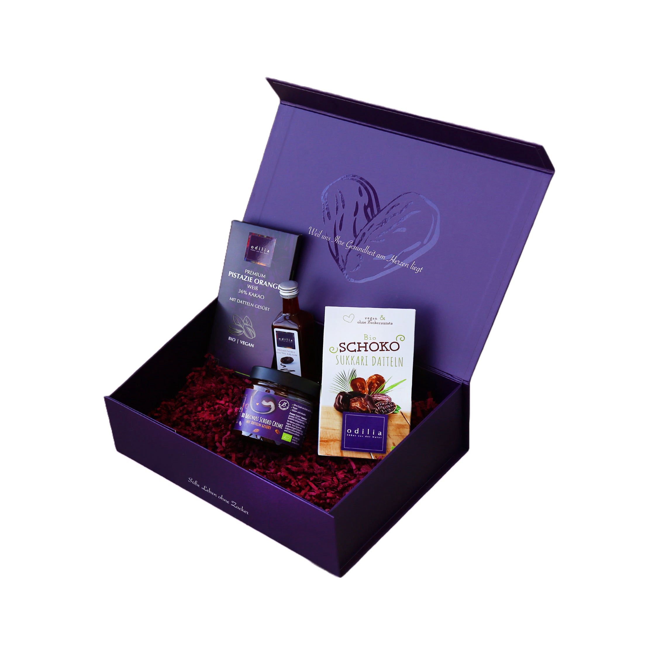 Geöffnete lila Geschenkbox mit Dattelprodukten, kleiner Flasche und Karte.