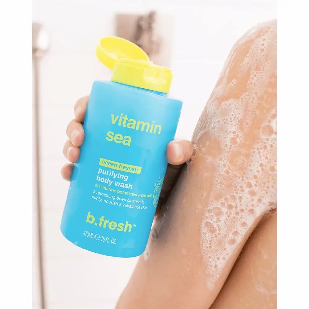 Blaues Duschgel mit gelbem Deckel. Aufschrift "Vitamin Sea" und "b.fresh". Flasche wird gehalten, Schaum auf Arm.