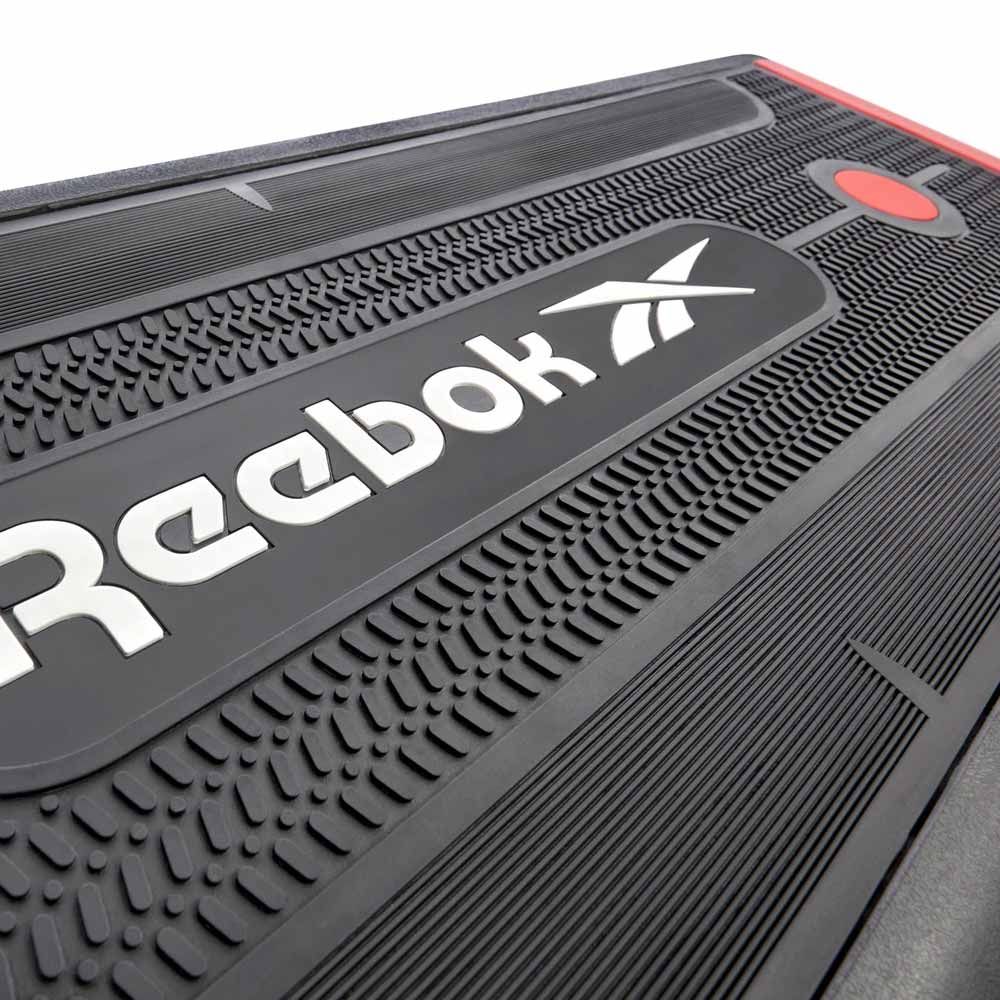 Schwarzer Reebok Step mit roter Akzentfarbe. Logo und Oberflächenstruktur sind deutlich sichtbar.