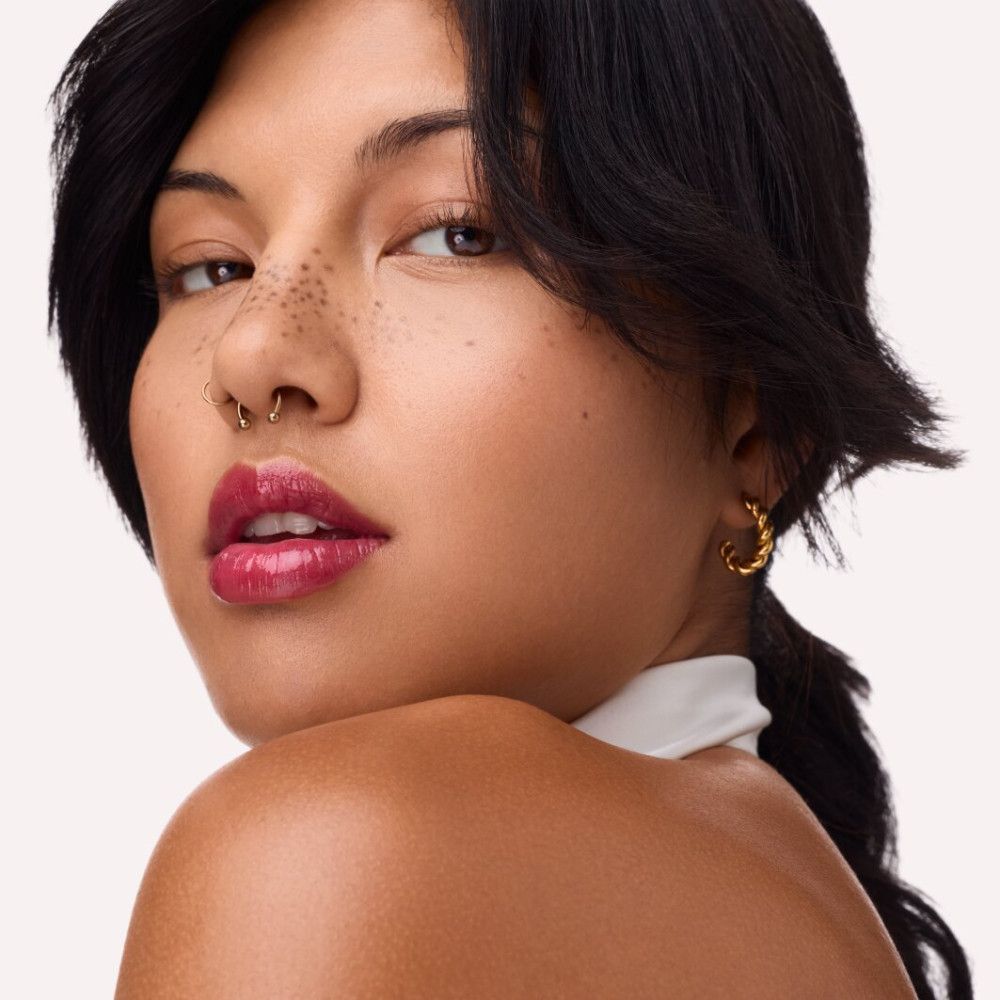 Porträt einer Frau mit rotem Lipgloss. Sichtbare Lippen, Nasenpiercing, Ohrringe.
