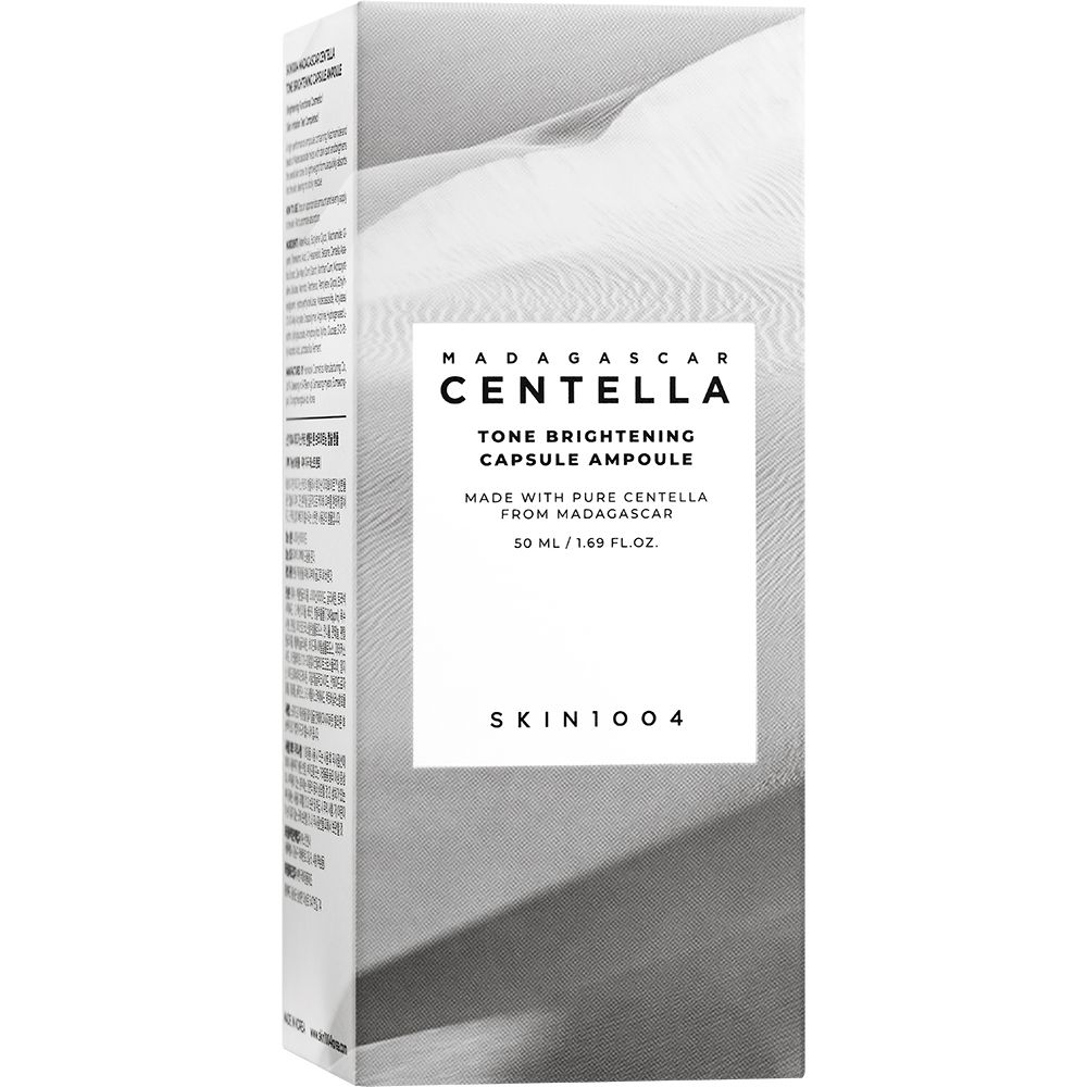 Hohe, rechteckige Verpackung mit Text und Logo. Text: MADAGASCAR CENTELLA, Tone Brightening Capsule Ampoule. Logo: SKIN1004.