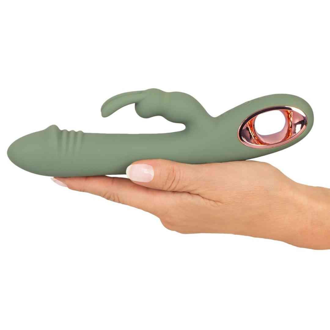 Grüner Vibrator mit Hasenohren, gehalten von einer Hand. Rosegoldfarbener Akzent am unteren Ende.